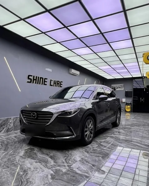 سيارة مازدا CX-9 رمادية أمام جدار شعار Shine Care داخل المركز